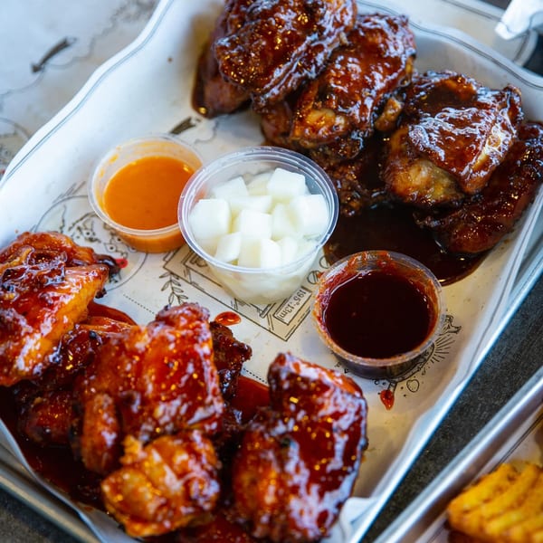 Goobne Chicken's glazed fried chicken pieces with dipping sauces and pickled radish on a tray.